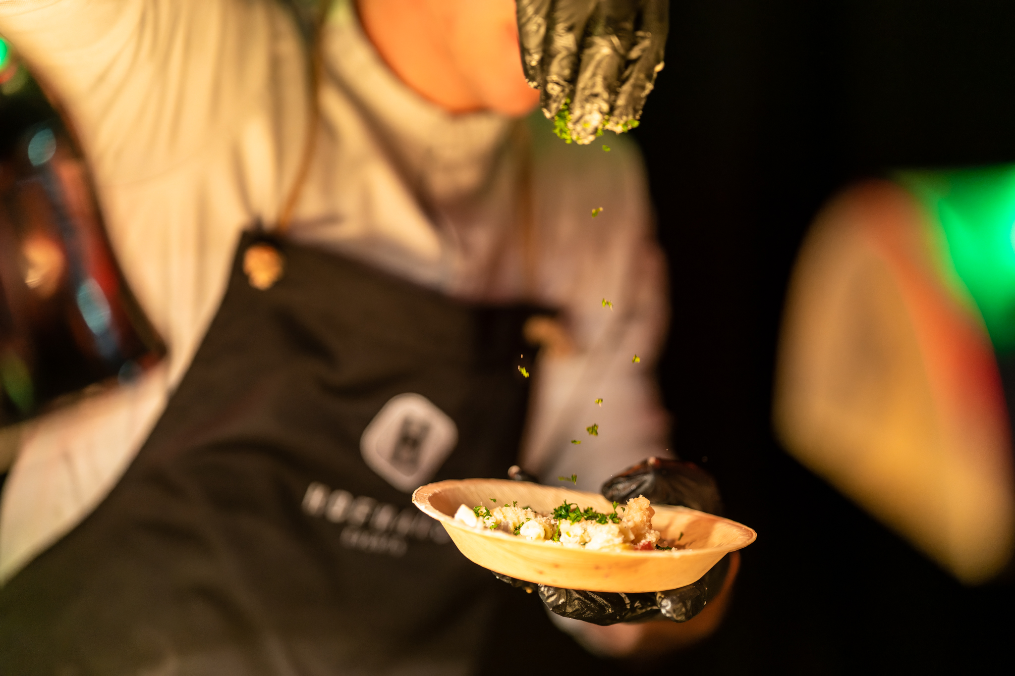Medewerker maakt een bordje op vanuit een food stand.